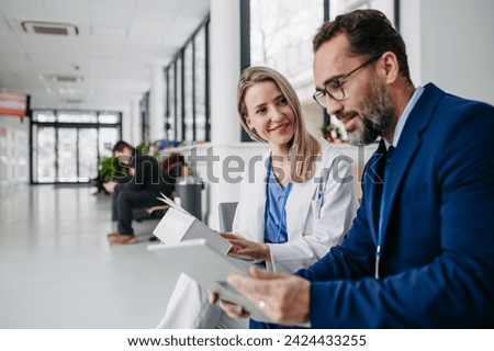 Pharmaceutical sales representative talking with doctor in medical building. Ambitious male sales representative presenting new medication on tablet.