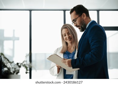 Pharmaceutical sales representative talking with female doctor in medical building. Hospital director consulting with healthcare staff. - Powered by Shutterstock