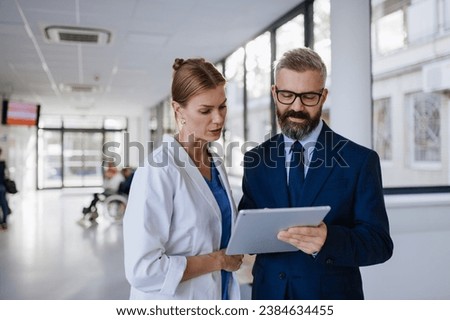 Pharmaceutical sales representative talking with female doctor in medical building. Hospital director consulting with healthcare staff.