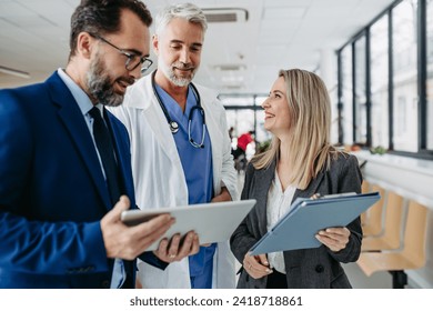 Pharmaceutical sales representatives meeting doctor in medical building. Hospital director and manager talking with head physician in modern clinic, hospital. - Powered by Shutterstock