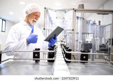 Pharmaceutical senior worker holding digital tablet for analysis and successfully controlling production of cosmetics products. - Powered by Shutterstock