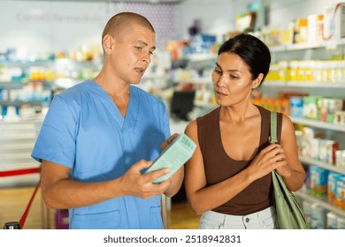 Pharmacist advises customer in a pharmacy, offers medicine for body care - Powered by Shutterstock