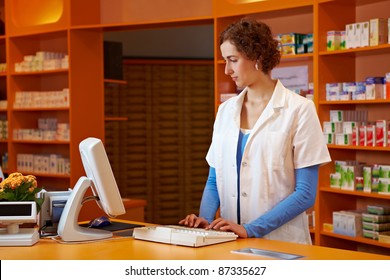 Pharmacist At Checkout Booth In Pharmacy Using A Computer