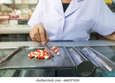 Pharmacist is counting pills on counting drugstore. - Powered by Shutterstock