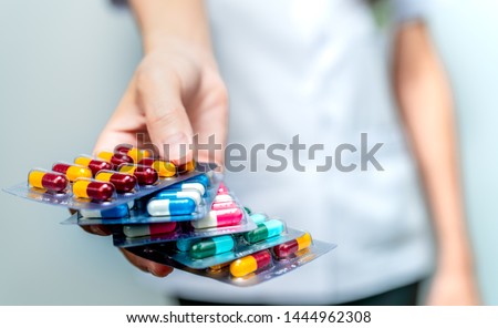 Pharmacist or doctor hand holding pack of antibiotic capsule pills and giving patient or people. Antibiotic drug overuse. Antimicrobial drug resistance. Community pharmacist. Drugstore background.