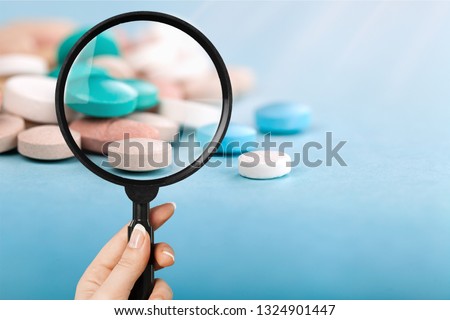 Pharmacist or expert on pharmaceutical inspection identifies pills. Testing, verification and determining pharmaceutical counterfeiting or fakes of medicines and medicinal substance quality concept