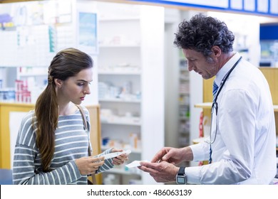 Pharmacist explaining prescriptions to customer in pharmacy - Powered by Shutterstock