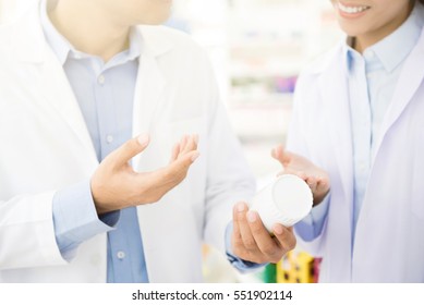 Pharmacist Holding Medicine Bottle And Discussing In Pharmacy