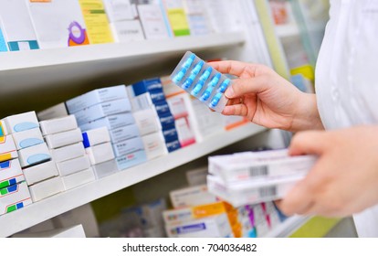 Pharmacist holding medicine box and capsule pack in pharmacy drugstore. - Shutterstock ID 704036482