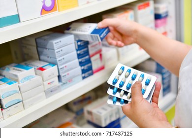Pharmacist holding medicine box and capsule pack in pharmacy drugstore. - Shutterstock ID 717437125