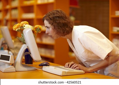 Pharmacist looking surprised at computer monitor in pharmacy