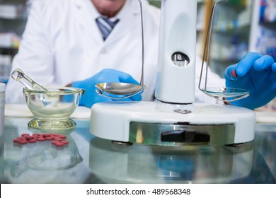 Pharmacist measuring tablets with pharmacy scale in pharmacy - Powered by Shutterstock