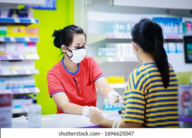 Pharmacist In Medical Face Mask Talking With A Customer At The Pharmacy Desk