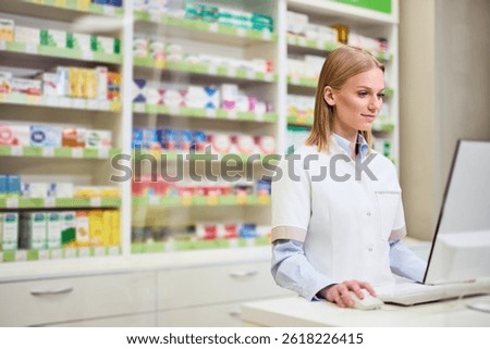 Pharmacist navigating pharmaceutical software surrounded by shelves of products in a pharmacy.