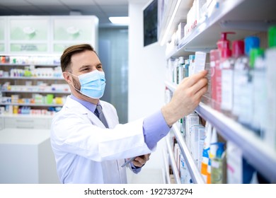 Pharmacist In Protection Mask Holding Tablet Computer And Checking Medicines In Pharmacy Shop.