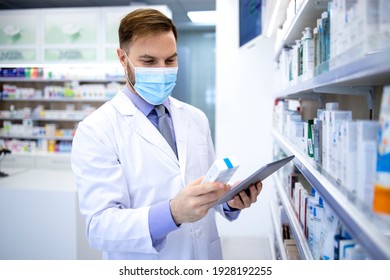 Pharmacist In Protection Mask Holding Tablet Computer And Checking Medicines In Pharmacy Shop.