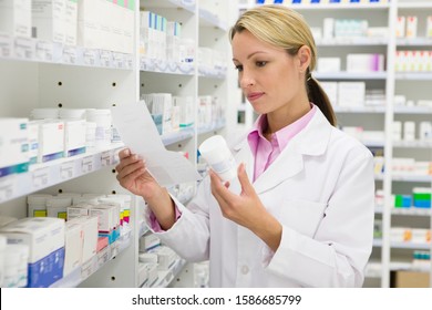 Un pharmacien lisant une ordonnance et une bouteille en pharmacie : photo de stock