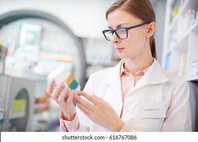 Pharmacist Reviewing Medicine Label On Bottle 