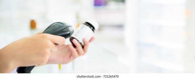 Pharmacist scanning medicine bottle with barcode scanner in pharmacy - panoramic banner with copy space on the right