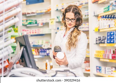 Pharmacist scanning price  on a medicine box - Female doctor working in a pharmacy - Powered by Shutterstock