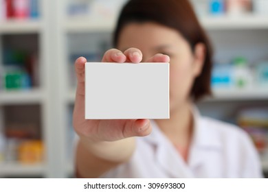 Pharmacist Showing White Blank Medicine Box With Pharmacy Store Shelves Background