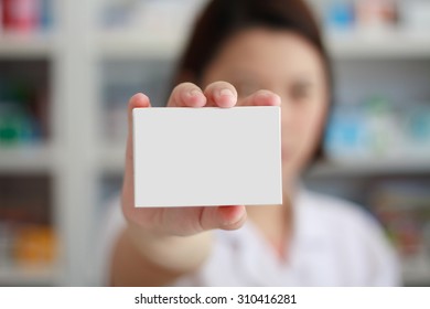 Pharmacist Showing White Blank Medicine Box With Pharmacy Store Shelves Background