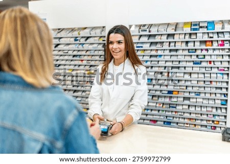 Pharmacist smiling while assisting customer with a contactless card payment at pharmacy counter, shelves of medications visible, representing modern retail healthcare service