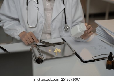 Pharmacist wearing lab coat and stethoscope is counting pills on metal drug counting tray and holding a medicine bottle in a pharmacy - Powered by Shutterstock