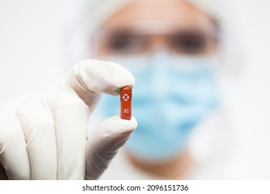 Pharmacist Wearing PPE Personal Protective Equipment,coveralls,face Mask,eyewear,glove,holding Red MERCK 82 Pill,selective Focus,antiviral Drug For Treating COVID-19 Disease,clinical Coronavirus Trial