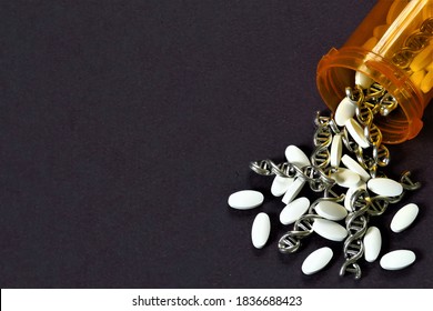 Pharmacogenetics (gene medicine): white tablets (pills) and silver spirals of DNA (RNA) spill out of an orange, plastic prescription bottle onto a black background.  Copy space.