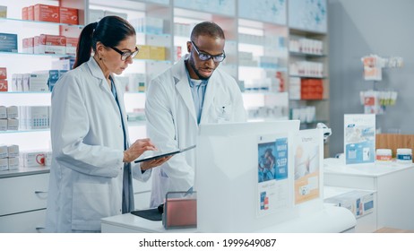 Pharmacy Behind The Checkout Counter: Black Male And Caucasian Female Pharmacists Talk About Medicine, Use Digital Tablet Computer. Medical Professionals In Drugstore With Health Care Products