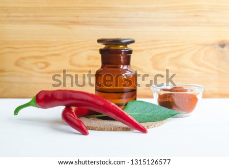 Pharmacy bottle with  red chili pepper extract (tincture, infusion, oil) and fresh chili pepper pods. Baldness, alopecia natural remedy and pain relief. Copy space.  

