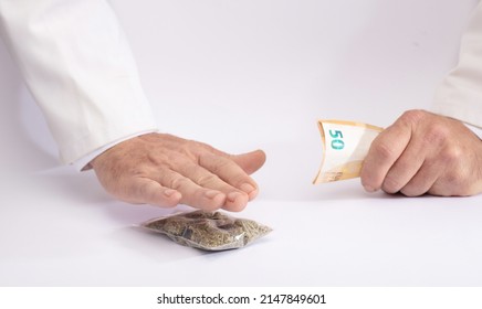 Pharmacy Clerk Hands Over A Bag Of Medical Marijuana And Takes The Collection Money With The Other Hand, On A White Counter