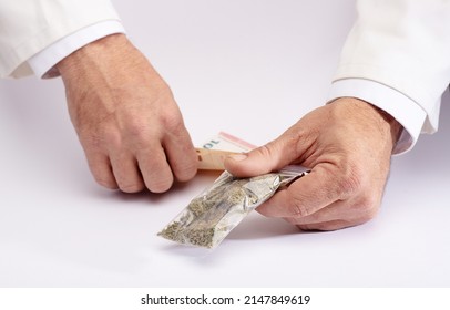 Pharmacy Clerk Hands Over A Bag Of Medical Marijuana And Takes The Collection Money With The Other Hand, On A White Counter