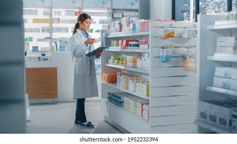 Pharmacy Drugstore: Beautiful Asian Pharmacist Uses Digital Tablet Computer, Checks Inventory of Medicine, Drugs, Vitamins, Health Care Products on a Shelf. Professional Pharmacist in Pharma Store - Powered by Shutterstock