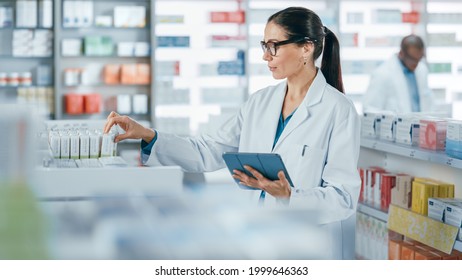 Pharmacy Drugstore: Beautiful Caucasian Pharmacist Uses Digital Tablet Computer, Checks Inventory of Medicine, Drugs, Vitamins, Health Care Products on a Shelf. Professional Pharmacist in Pharma Store