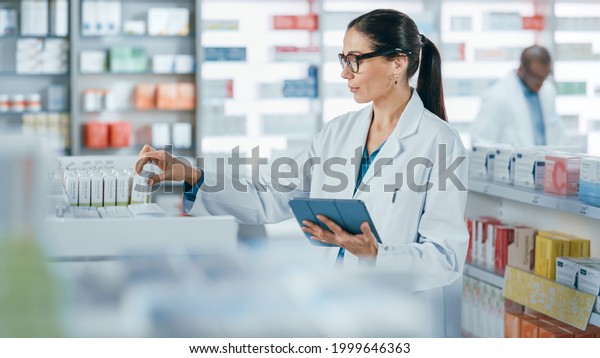 Pharmacy Drugstore: Beautiful Caucasian Pharmacist\
Uses Digital Tablet Computer, Checks Inventory of Medicine, Drugs,\
Vitamins, Health Care Products on a Shelf. Professional Pharmacist\
in Pharma Store