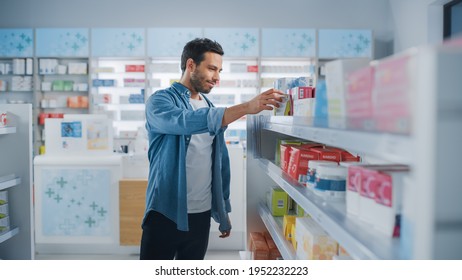 Pharmacy Drugstore: Portrait Of Handsome Latin Man Choosing To Buy Medicine Browsing Through The Shelf, Successfully Finds What He Needs. Modern Pharma Store Health Care Products