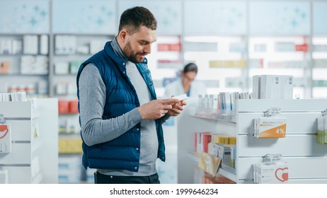 Pharmacy Drugstore: Portrait Of A Handsome Young Man Choosing To Buy Medicine, Drugs, Vitamins. Apothecary Full Of Health Care Products, Pill Bottles, Sport Supplement Packages With Modern Design