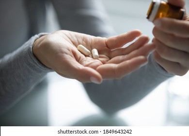 Pharmacy and healthcare. Close up of young female hands holding opened pill bottle and two soft-shelled capsules taking medicine for flu, influenza, painkiller, vitamin complex, oral contraceptives - Shutterstock ID 1849643242
