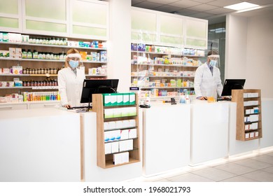 Pharmacy interior with medicines and pharmacist cashiers working during corona virus pandemic.
