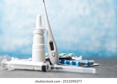 Pharmacy medicine, nasal spray, digital thermometer, syringe, pills in blister pack and medical mask on blue background. - Powered by Shutterstock