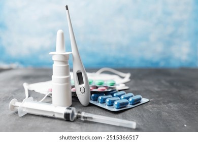 Pharmacy medicine, nasal spray, digital thermometer, syringe, pills in blister pack and medical mask on blue background. - Powered by Shutterstock