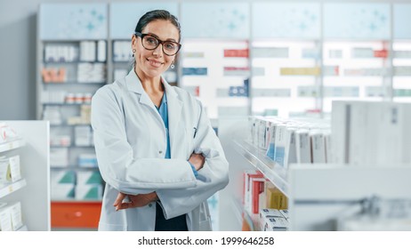 Pharmacy: Portrait of Beautiful Professional Caucasian Female Pharmacist Wearing Glasses, Crosses Arms and Looks at Camera Smiling Charmingly. Drugstore Store with Shelves Health Care Products - Powered by Shutterstock