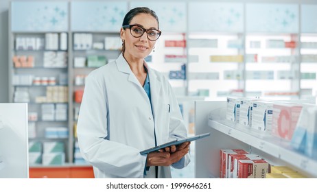 Pharmacy: Portrait of Professional Beautiful Caucasian Female Pharmacist Uses Digital Tablet Computer, Checks Medicine Inventory, Looks at Camera, Smiles Charmingly. Drugstore Health Care Products