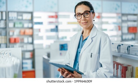 Pharmacy: Portrait Of Professional Beautiful Caucasian Female Pharmacist Uses Digital Tablet Computer, Checks Medicine Inventory, Looks At Camera, Smiles Charmingly. Drugstore Health Care Products