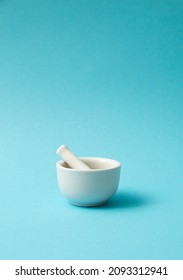 Pharmacy white ceramic stone mortar with pestle on blue background. Minimalist concept design.