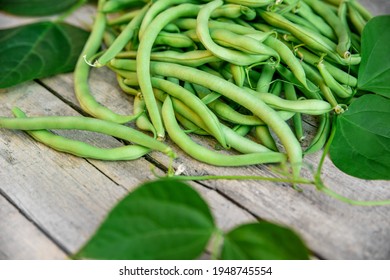 Phaseolus vulgaris, fresh raw common beans, green bush beans with leaves on wooden table