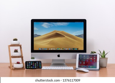 PHATTHALUNG, THAILAND - APRIL 21, 2019: IMac Computer, Keyboard, Magic Mouse, IPhone X, IPad Mini, Plant Vase And Cactus Pots On Wooden Table, Created By Apple Inc.