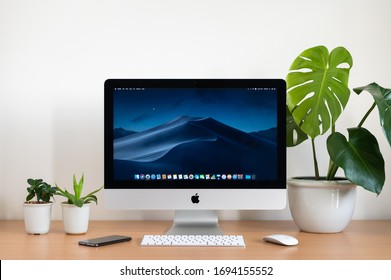 PHATTHALUNG, THAILAND - JANUARY 12, 2020: iMac computer, keyboard, magic mouse, monstera plant pot and small plant pots on wooden table, created by Apple Inc.